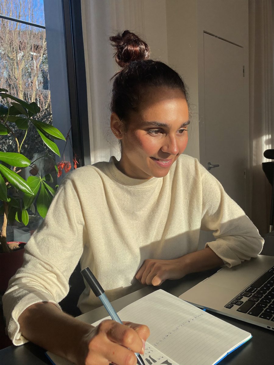 Woman writing notes at a sunlit desk