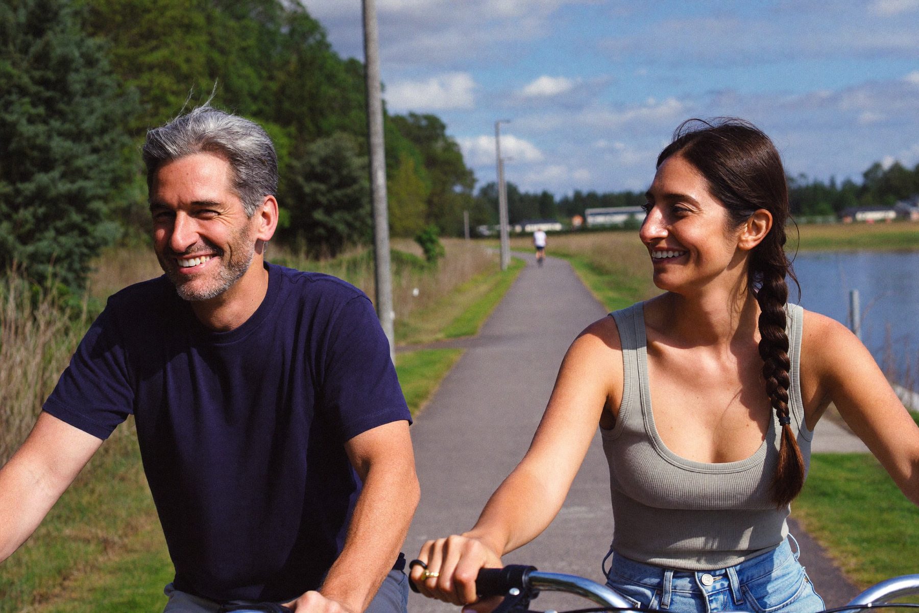 A couple laughing while riding bikes on a lakeside path