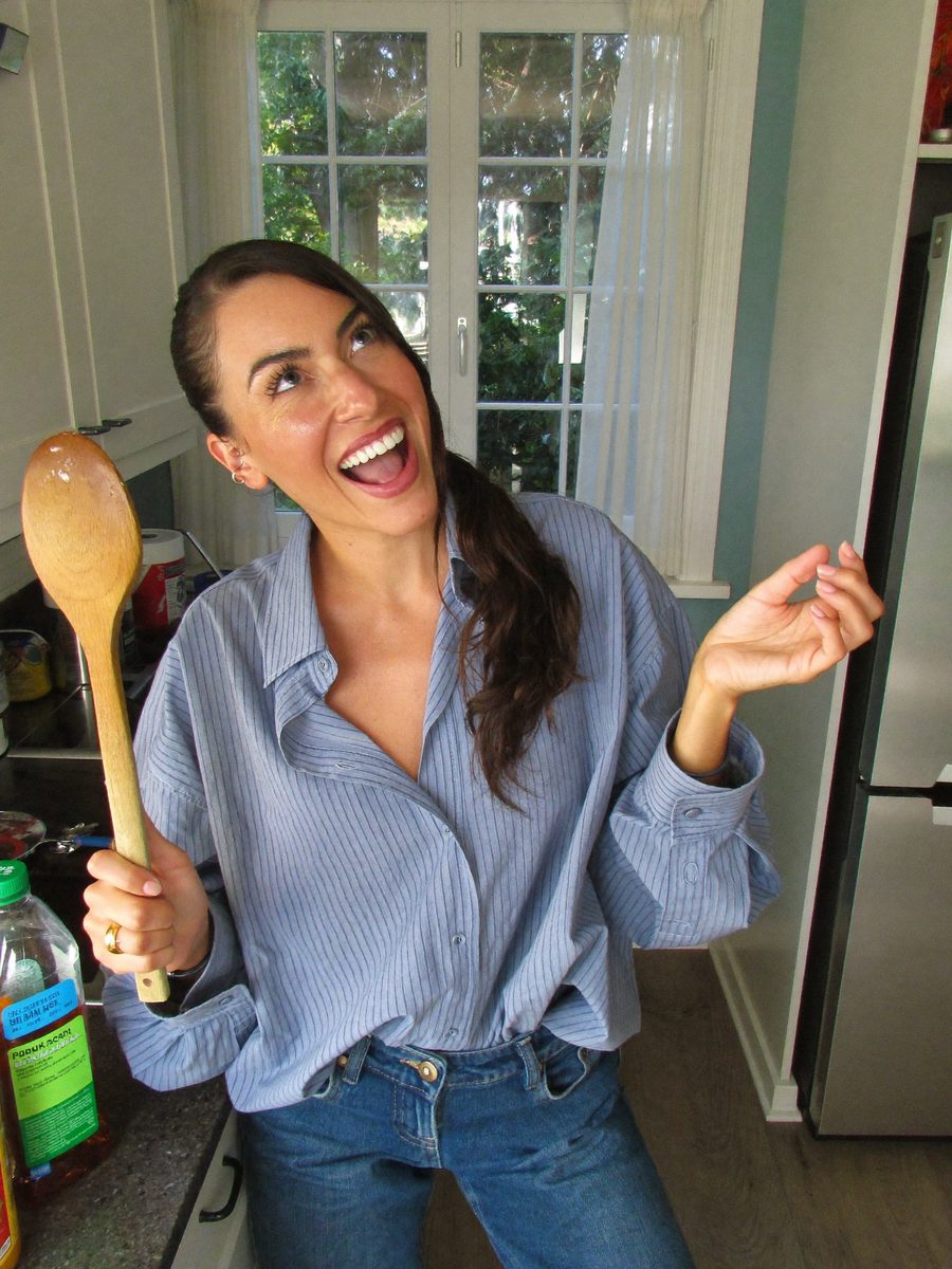 Woman dancing in her kitchen holding a wooden spoon