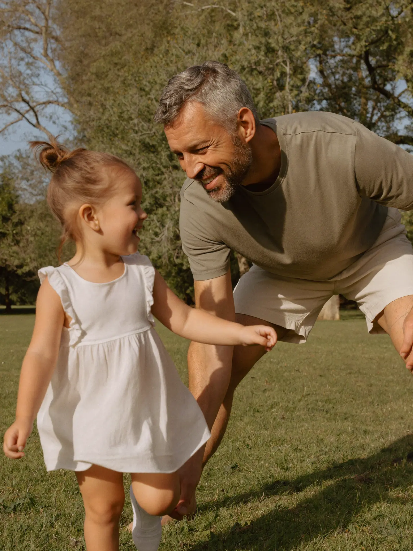 Smiling man playing with a child in a sunny park